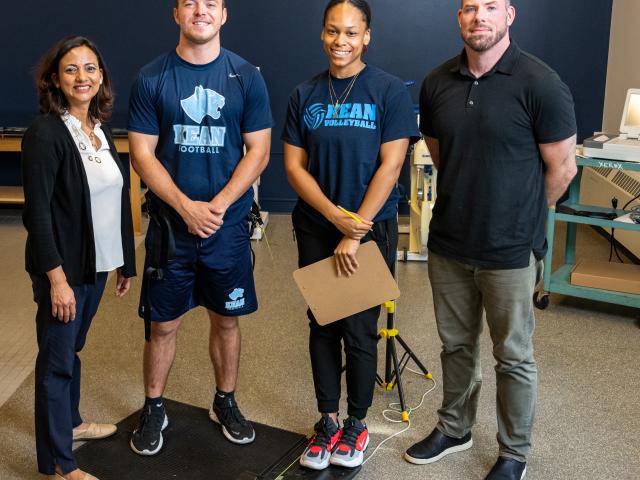 Four people posing two of them wearing Kean athletic wear