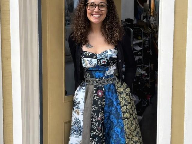 Woman with dark and glasses wearing printed dress smiling