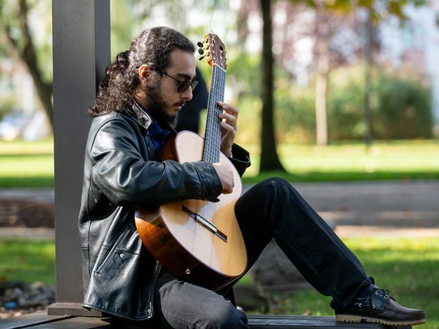Student Sitting on Bench and Playing Guitar