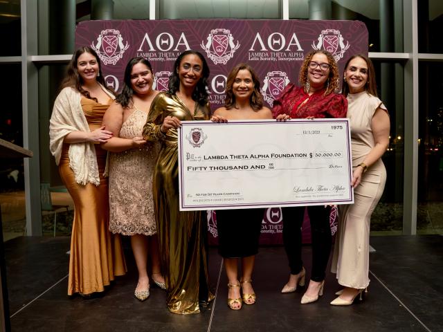 Members of Lambda Theta Alpha holding oversized check for $50,000