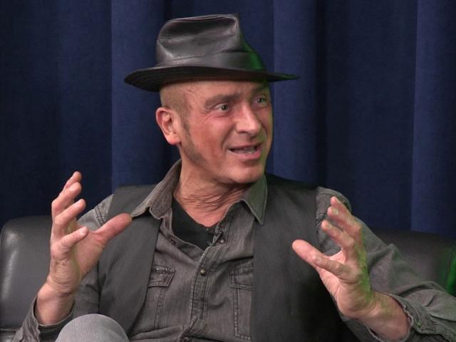 male wearing a black leather hat, black denim shirt with a black vest