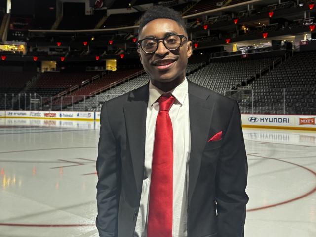 Man in a suit standing in a hockey arena