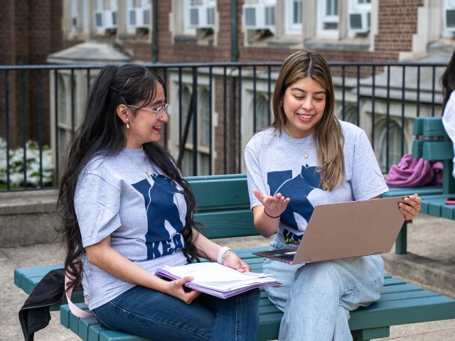 Two adult learners sit on a bench on Kean's Jersey City campus