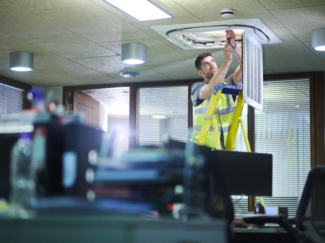 An image of a custodial worker installing new light bulbs