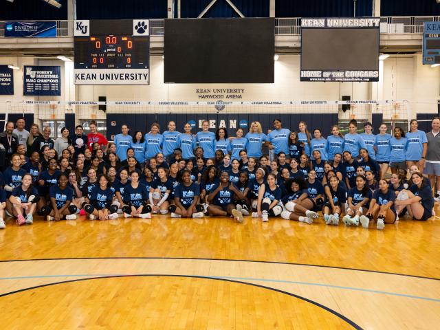 Volleyball players and coaches standing and kneeling on a court