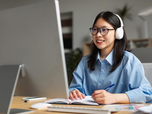 An adult learner takes notes during an online class