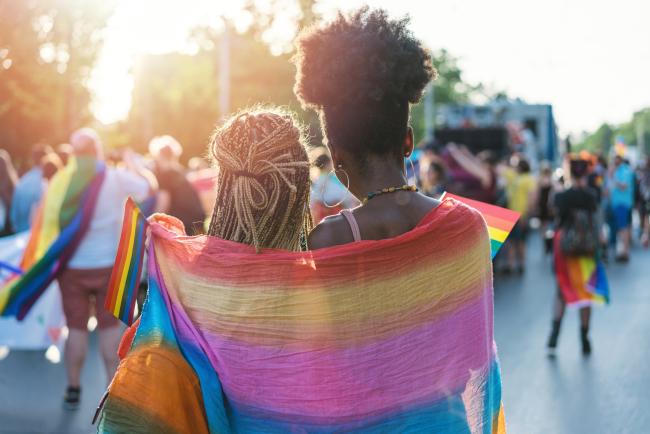 Two girls wrapped in a pride flag at pride parade