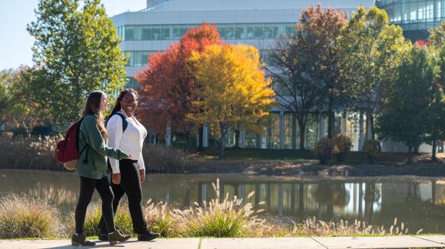 Kean Students walk near the STEM building against a backdrop of Fall foliage
