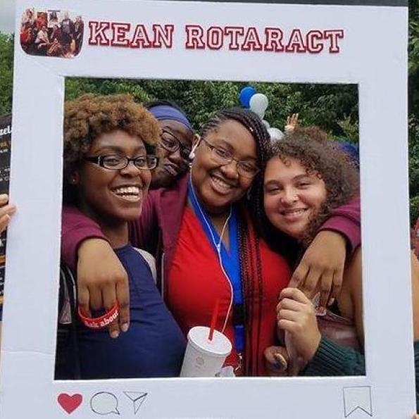 Three students smiling in a Kean Rotaract photo frame during a Kean event