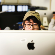 Top half of student head visible above an Apple computer