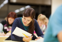 Student with her head down looking carefully at a piece of paper, holding a pencil