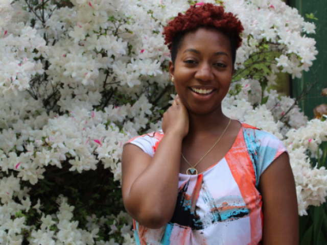 English alumna Schane Flowers standing in front of a tree