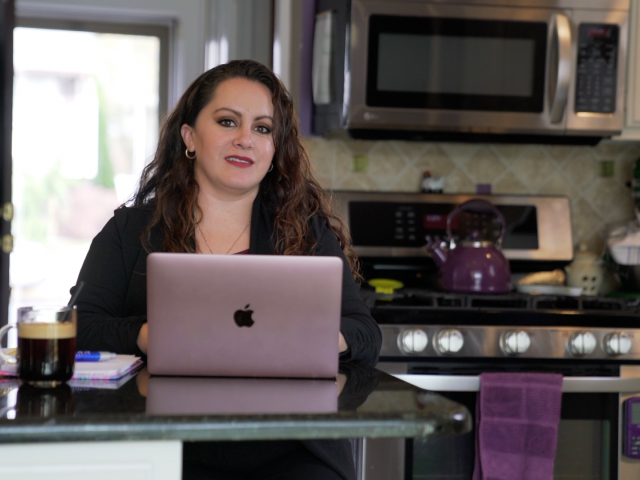 A Kean Online student with a laptop in her kitchen.