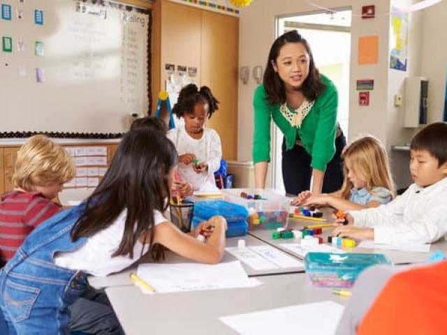 In a 4th grade classroom a teacher hovers over a math lesson