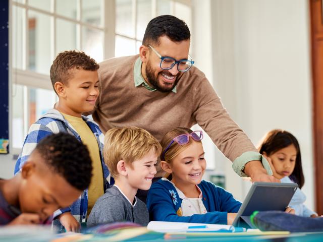 An educational technologist instructs students in tablet use. 