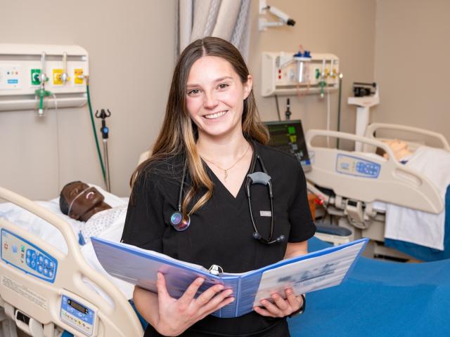 A Kean nursing student pictured with an open binder during a clinical rotation