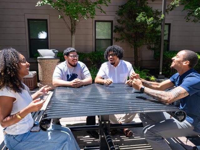 Kean Jersey City students gather round a table on the West Campus Village patio