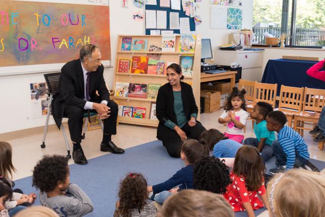 Dr. Farahi looks on smiling to the classroom full of children. 