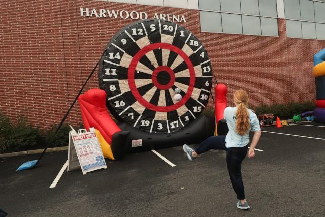 A girl plays a giant game of darts. 