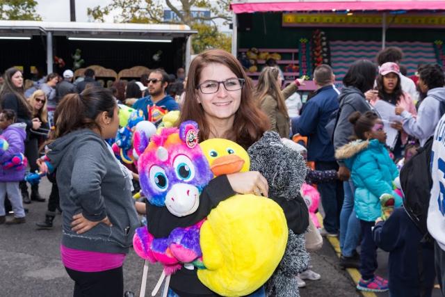 A girl holds a stuffed animal at the carnival games. 