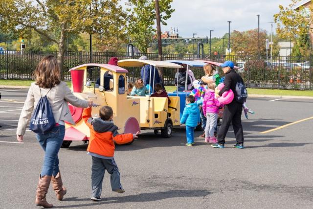 A small train picks up kids for a ride around the parking lot. 