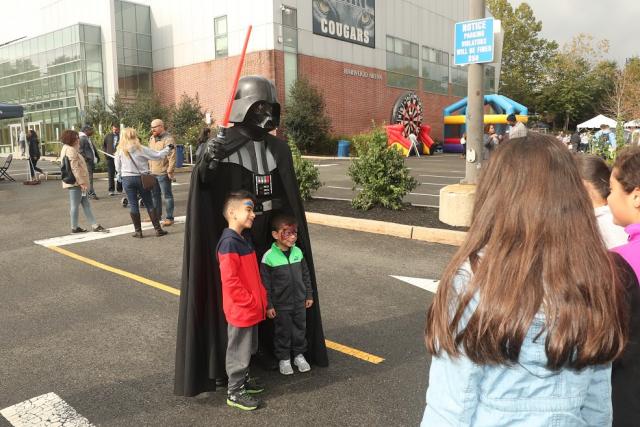 A dressed up Darth Vader poses with two small boys. 