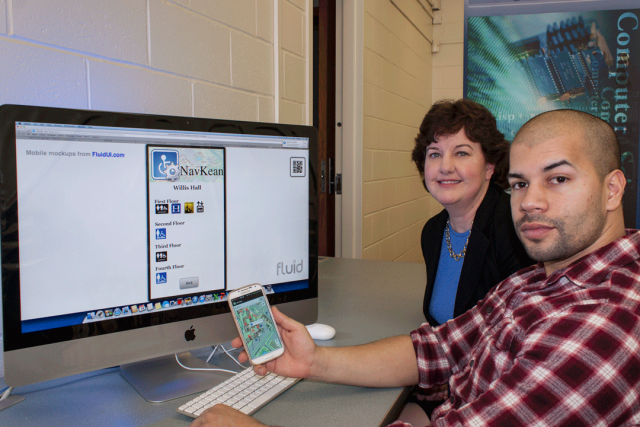 Pat Morreale, Ph.D. with student JimenezL holding a cell phone, sitting in front of a wide angle computer screen