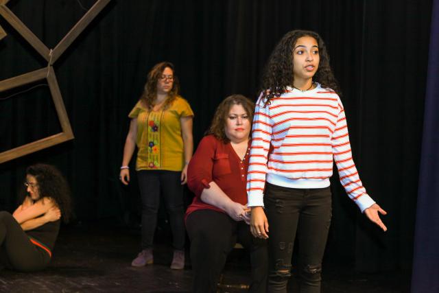 Three actresses stand on stage acting the monologues of those affected by domestic violence.