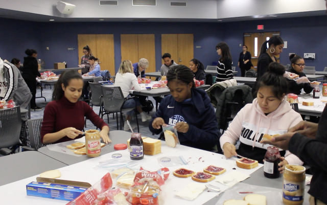 A whole room of students come together to make sandwiches