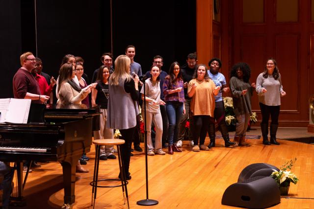 O'Hara stands on stage with Kean students in practice attire.