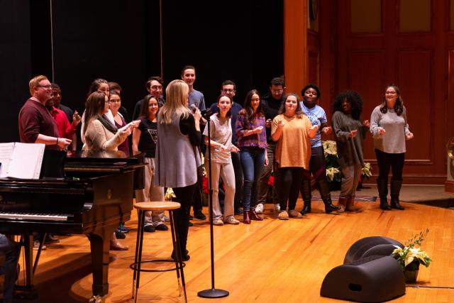 O'Hara stands on stage with Kean students in practice attire.