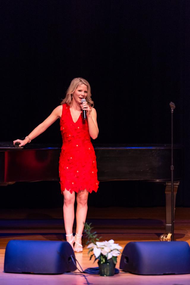 Kelly O'Hara stand on center stage with microphone to her mouth.