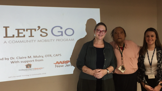 Students and Professor Mulry pose in front of Let's Go presentation