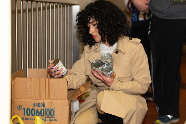 Girl kneels down to organize canned good into boxes to bring to food pantry.