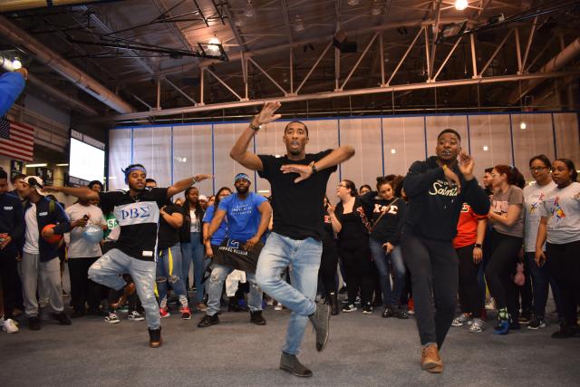 Students perform a dance routine while others look on. 