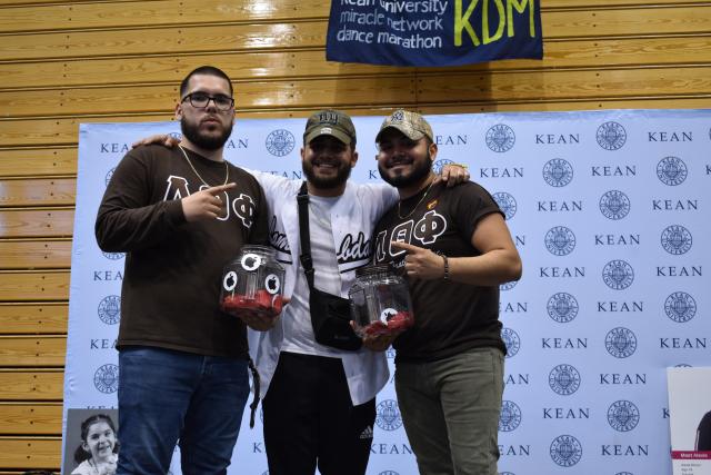 Students in a fraternity pose on stage. 