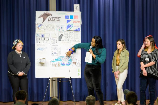 Students present their work on stage. 