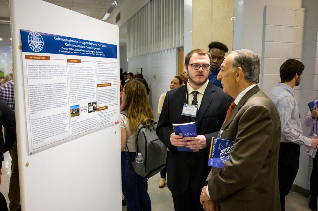 A student shows Dr. Farahi his research work. 