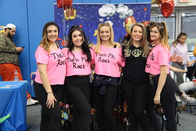 Students in a sorority pose with their matching shirts representing their team. 