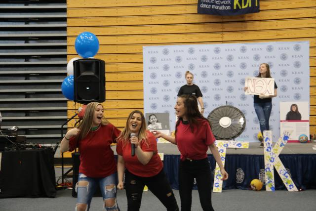 Students in a soroity perform their dance routine with microphone in hand. 