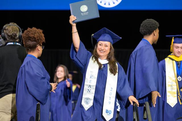 A Kean University graduate smiles after receiving her diploma cover.