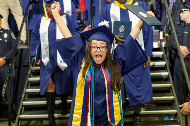 A Kean University student cheers after receiving her diploma at commencement.