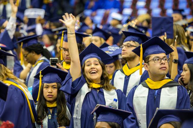 A student waves to family and friends at Kean University's Undergraduate Commencement