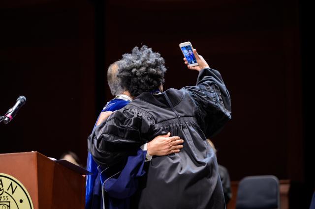 Commencement Speaker Nancy Giles takes a selfie on stage with Kean President Dawood Farahi.