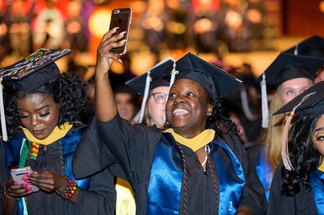 A student takes a selfie at her seat at Nathan Weiss Graduate College Commencement.