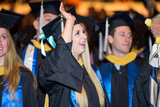 A student waves to family from her seat at the Nathan Weiss Graduate College Commencement.