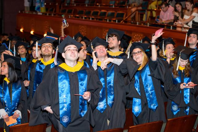 Students search for family and friends in the crowd at the graduate college commencement.