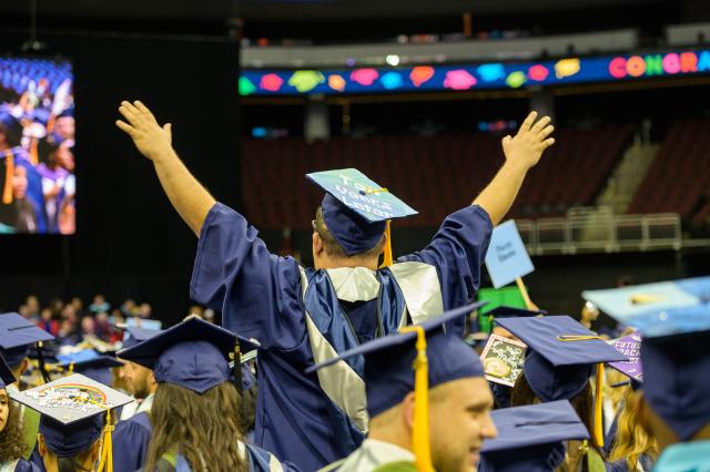 graduate waving arms at commencement