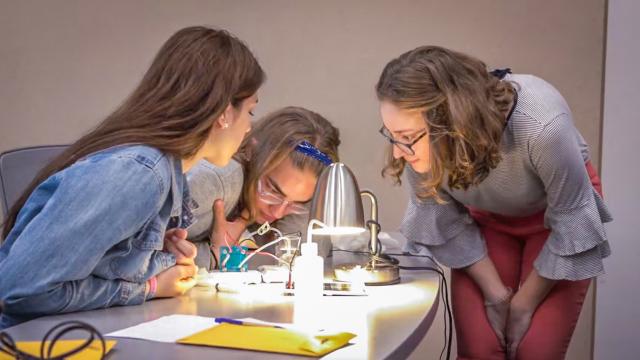 Three students collaborate on a renewable energy experiment.