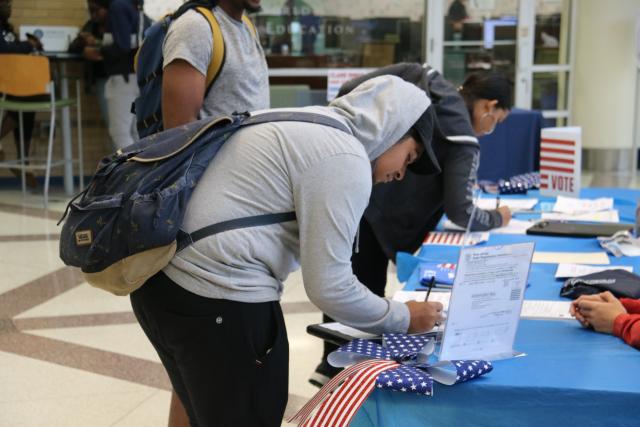 Student with backpack signing voter registration form